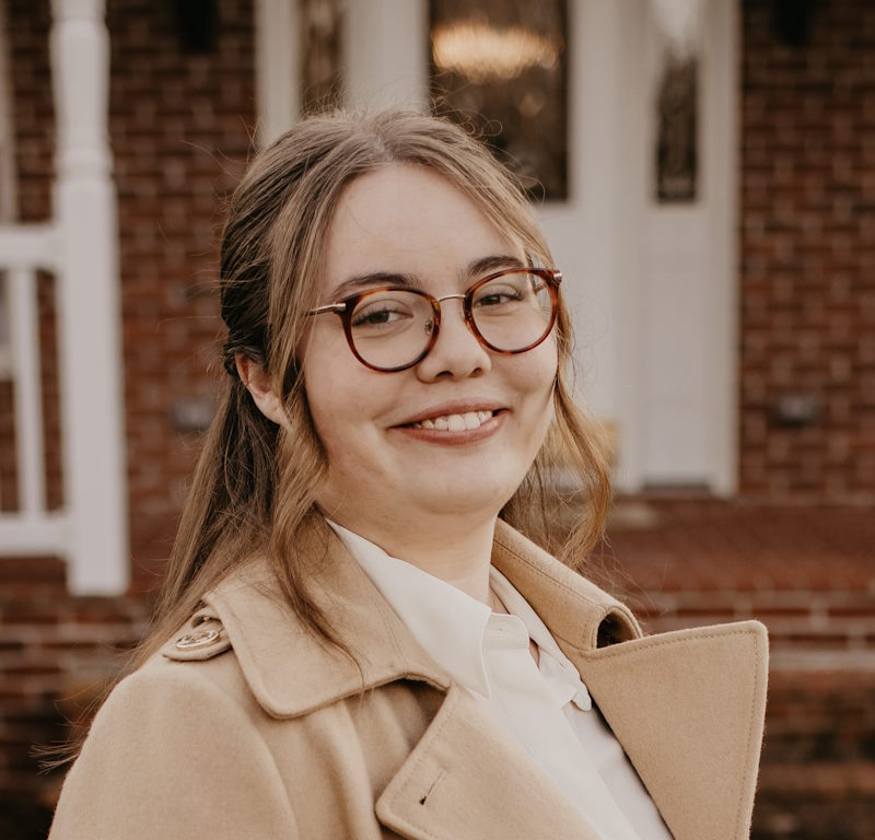 A woman wearing glasses and smiling into the camera