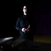 Man half lit standing on a dark stage. 