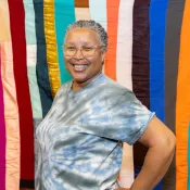 Person standing in front of a colorful quilt.