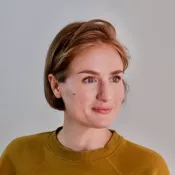 A woman at a 3/4 angle smiling and looking away from the camera