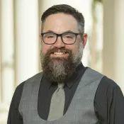 A man wearing glasses and smiling into the camera