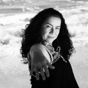 Woman on the beach holding a hand out toward the camera.