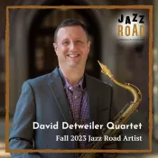 A man smiling into the camera and holding a saxophone