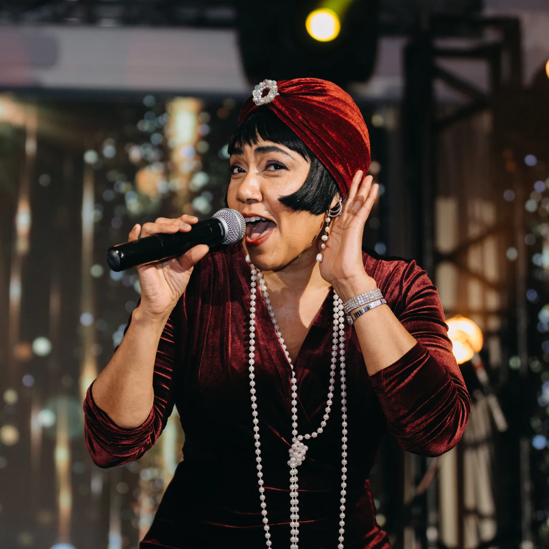 A woman singing with her hand cupped to her ear