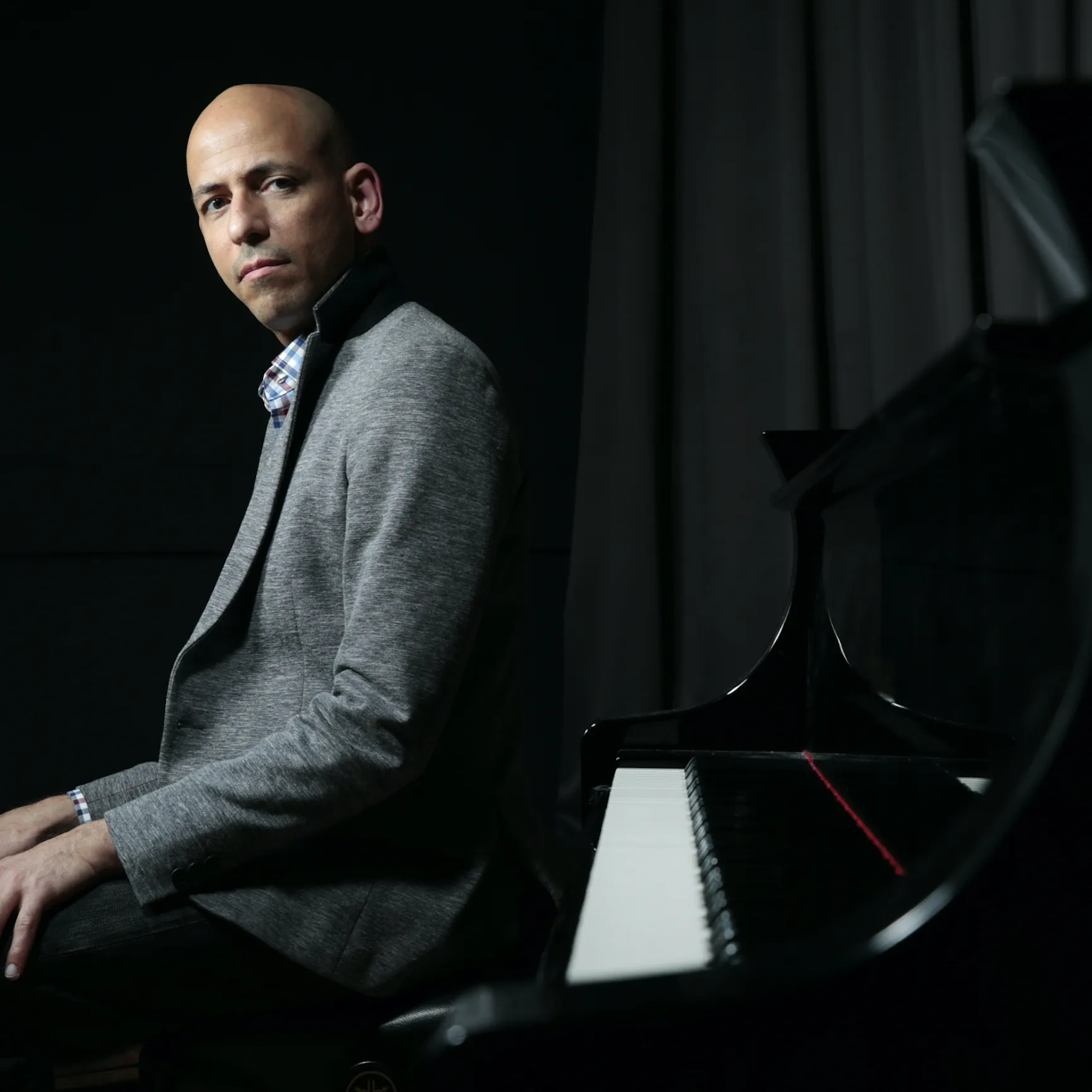 A man sitting with his back to the piano