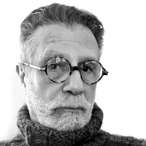 Man wearing circular glasses and dark turtleneck.