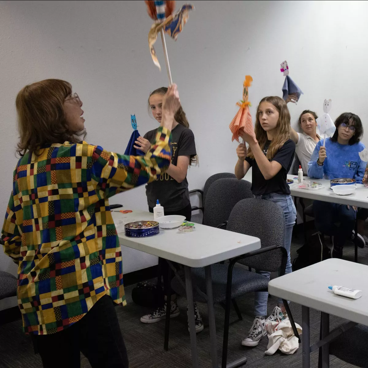 A teacher and group of students holding puppets