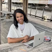 A woman seated at a bench with a laptop in front of her