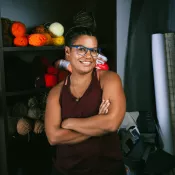 A person smiling into the camera with their arms crossed