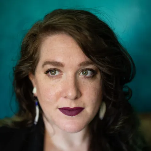 Woman with long dark hair and dark lipstick looking up and to the side.