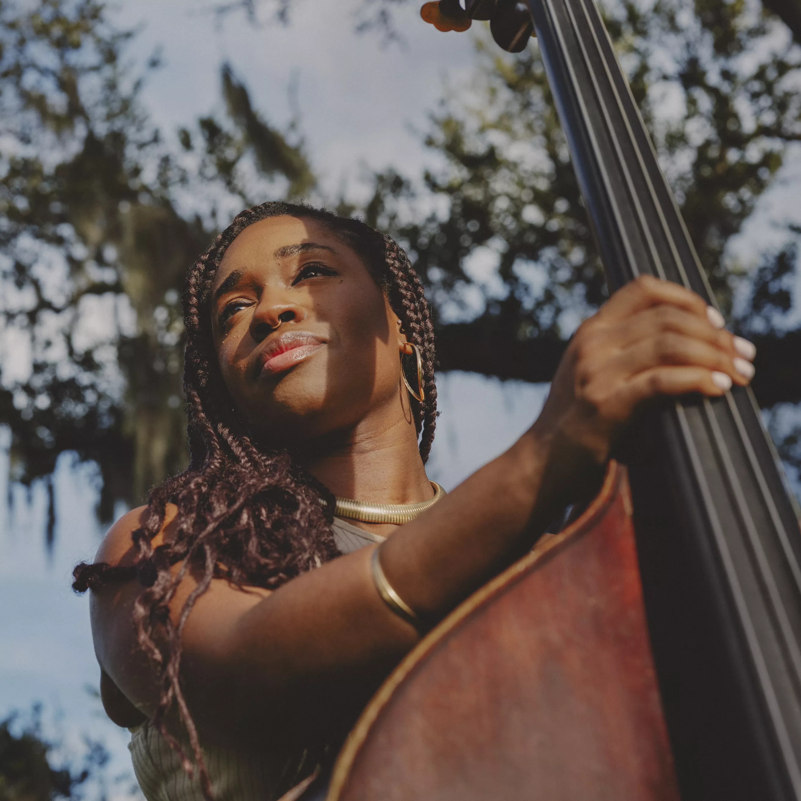 A woman holding an upright bass and looking away from the camera
