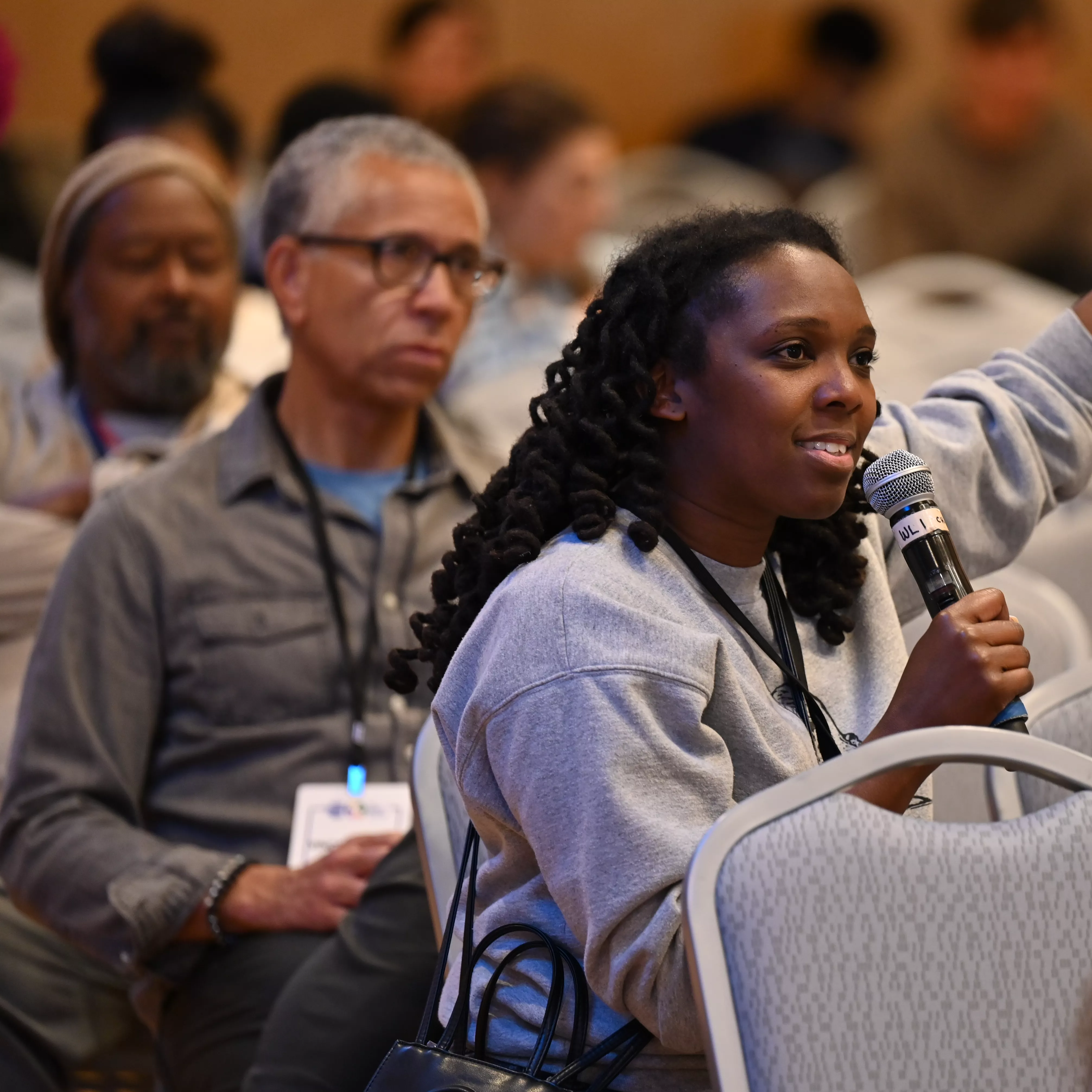 A woman in the audience holding a microphone while asking a question